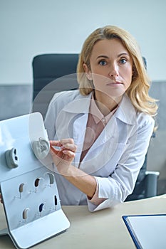 Serious otolaryngologist showing artificial human ear