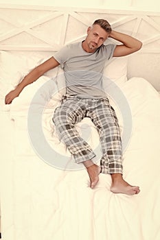 Serious pajama man rest in bed wakening after sleep in morning, resting photo