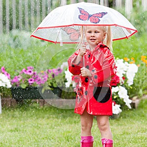 Serious pensive pretty little girl in red raincoat with umbrella