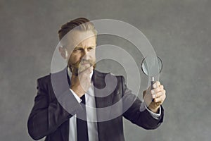 Serious pensive thoughtful man businessman looking through magnifying glass