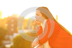 Serious pensive woman in a balcony in winter at sunset