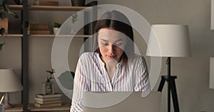 Serious pensive woman working on laptop doing routine telecommute job