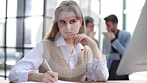 Serious pensive young business lady economist is thinking which decision to make at her modern light work place in