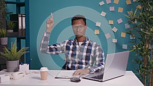 Serious person pointing up with index finger at office desk