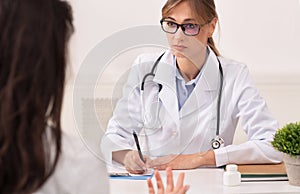 Serious Physician Woman Seeing Female Patient Sitting At Workplace