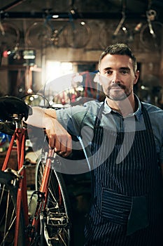 Serious, portrait and repair man in bicycle shop working in store or cycling workshop. Face, bike mechanic and confident