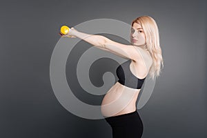 Serious pregnant woman training with dumbbells