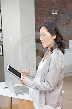 Serious pregnant woman using tablet