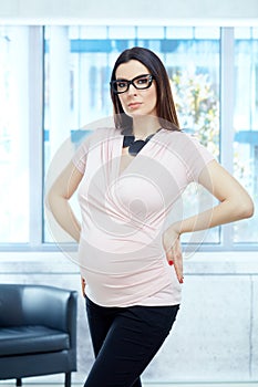 Serious pregnant woman working in modern office