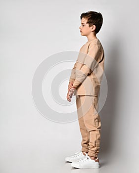 Serious preteen boy child standing sideway looking forward over studio wall photo