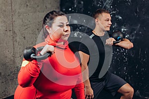 Serious pretty girl holding the weight and working out indoors