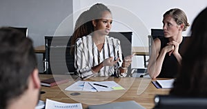 Serious pretty young African American businesswoman talking to nodding colleagues