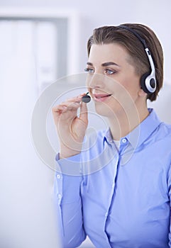 Serious pretty young woman working as support phone operator with headset in office