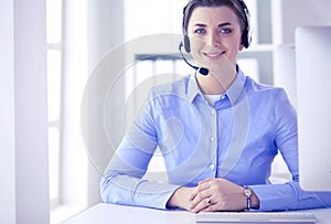 Serious pretty young woman working as support phone operator with headset in office