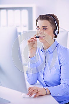 Serious pretty young woman working as support phone operator with headset in office