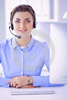 Serious pretty young woman working as support phone operator with headset in office