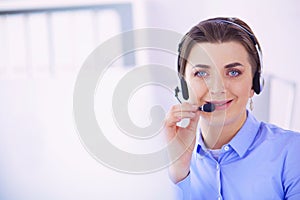 Serious pretty young woman working as support phone operator with headset in office
