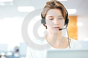 Serious pretty young woman working as support phone operator