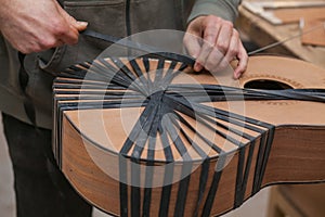 Serious professional guitar-maker working with unfinished guitar at workshop