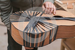 Serious professional guitar-maker working with unfinished guitar at workshop