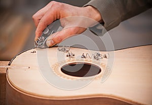 Serious professional guitar-maker working with unfinished guitar at workshop