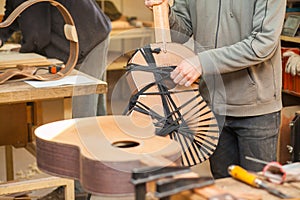 Serious professional guitar-maker working with unfinished guitar at workshop