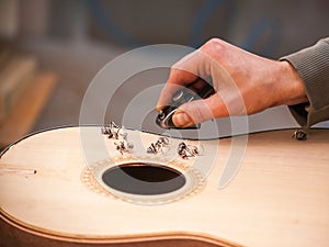 Serious professional guitar-maker working with unfinished guitar at workshop