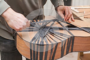 Serious professional guitar-maker working with unfinished guitar at workshop