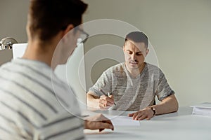 Serious professional man consulting client in office. Two mens having meeting, making business conversation. Insurer