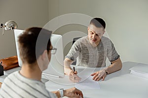 Serious professional man consulting client in office. Two mens having meeting, making business conversation. Insurer