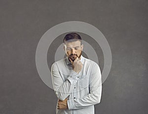 Serious puzzled sad man thinking looking down keeping fist at chin studio shot