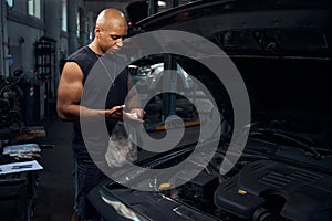 Serious repairman cleaning his hands from motor oil and grease with rag