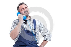 Serious repairman solving a work problem on telephone