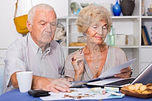 Serious retired couple calculating bills