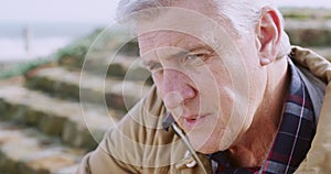 A serious, sad and depressed man staring and gazing seriously while standing outdoors. Upset, anxious and unhappy man