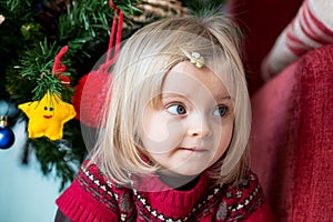 Serious sad or thinking young baby caucasian blonde girl portrait at home near christmas tree