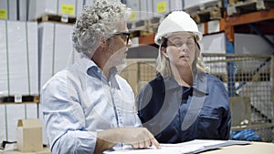 Serious safety inspector checking warehouse with female worker.
