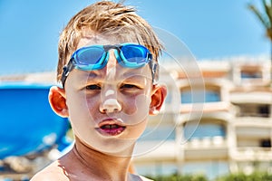 Serious schooler with goggles stands against hotel building