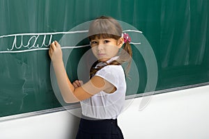 Serious schoolgirl standing at blackboard