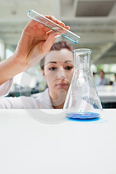 A serious science student pouring liquid