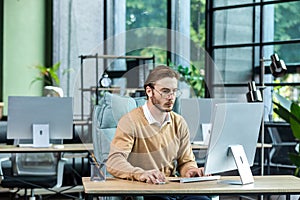 Serious and scorn-centered man in the office at work with a computer, man typing thoughtfully on keyboards, businessman