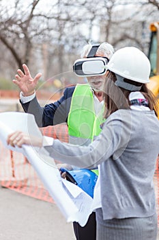 Serious senior architect or businessman using virtual reality goggles to visualize construction project on a construction site