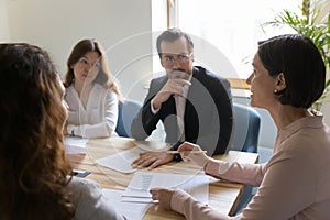 Serious senior company executive woman talking to employees on meeting