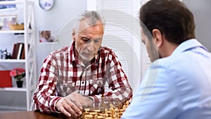 Serious senior male playing chess with opponent, complicated competition, sport