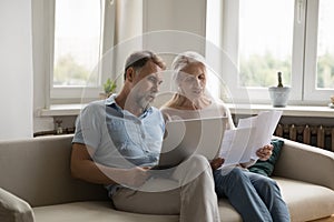 Serious senior retired family couple using laptop for domestic payment