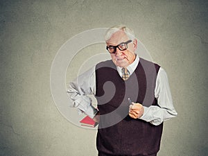 Serious senior strict teacher holding book and pen