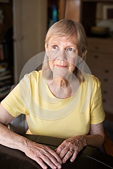 Serious senior woman seated at table