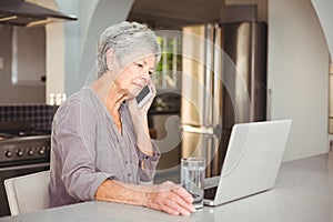 Serious senior woman talking on mobile phone