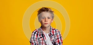 Serious seriously calm cute caucasian teenage boy looking at camera, isolated on yellow background