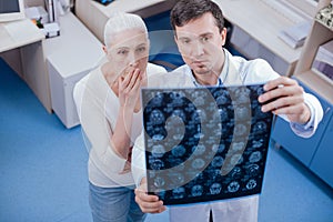 Serious shocked woman looking at her brain X ray images